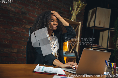 Image of Young woman working in modern office using devices and gadgets. Making reports, analitycs, routine processing tasks