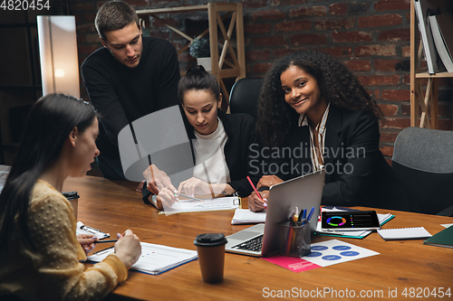 Image of Colleagues working together in modern office using devices and gadgets during creative meeting