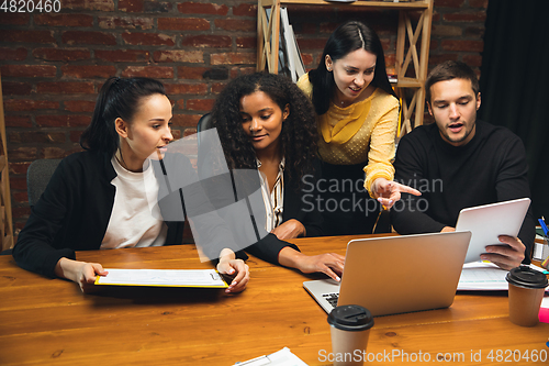 Image of Colleagues working together in modern office using devices and gadgets during creative meeting