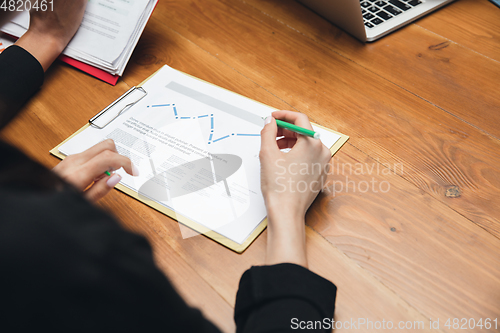 Image of Close up hands of people, managers working in modern office using modern devices and flipchart with graphics