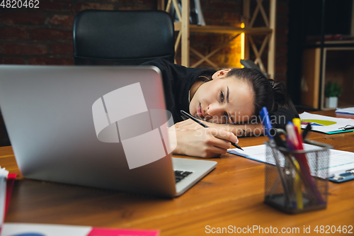 Image of Young woman working in modern office using devices and gadgets. Making reports, analitycs, routine processing tasks