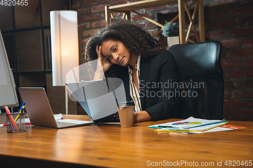 Image of Young woman working in modern office using devices and gadgets. Making reports, analitycs, routine processing tasks