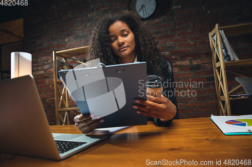 Image of Young woman working in modern office using devices and gadgets. Making reports, analitycs, routine processing tasks