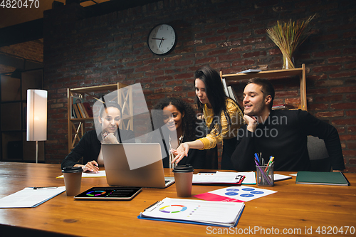 Image of Colleagues working together in modern office using devices and gadgets during creative meeting