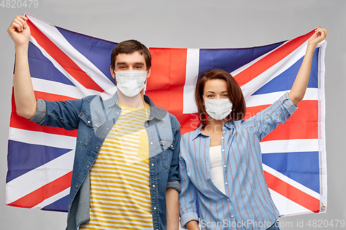 Image of couple in face masks holding flag of england