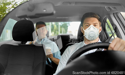 Image of taxi driver in mask driving car with passenger