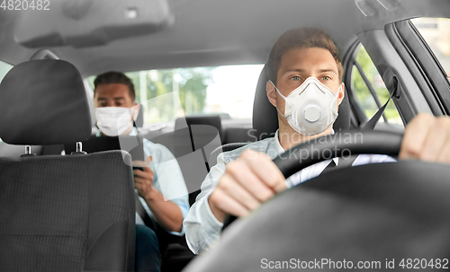 Image of taxi driver in mask driving car with passenger