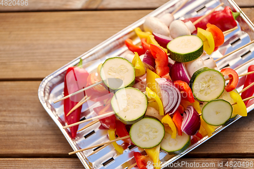 Image of close up of vegetables on skewers on foil grill