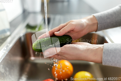 Image of woman washing fruits and vegetables in kitchen