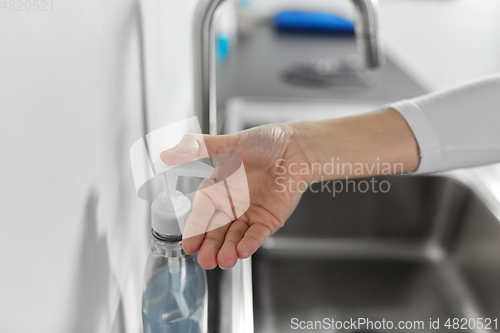 Image of woman washing hands with liquid soap in kitchen