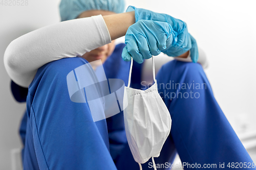 Image of sad doctor or nurse holding protective face mask