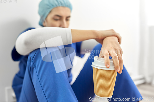 Image of sad doctor or nurse with cup of takeaway coffee