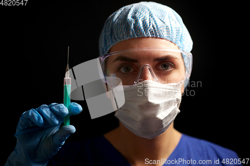 Image of doctor in face mask and goggles holding syringe