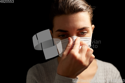 Image of sick woman adjusting protective medical face mask