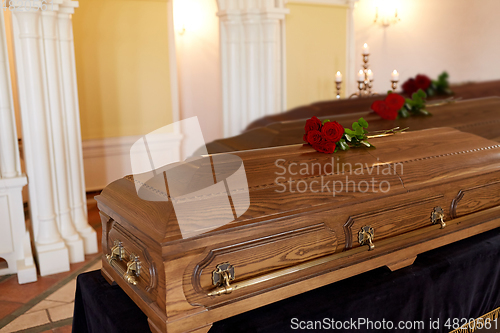 Image of red rose flowers on wooden coffins in church