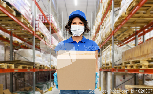 Image of delivery woman in mask with box at warehouse
