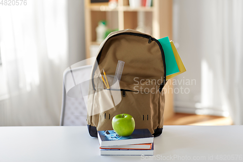 Image of school backpack with books and apple on table