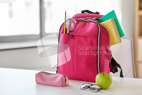 Image of pink backpack, apple and school supplies on table