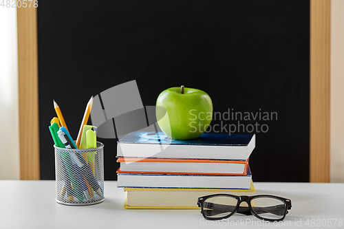 Image of books, apple and school supplies on table at home