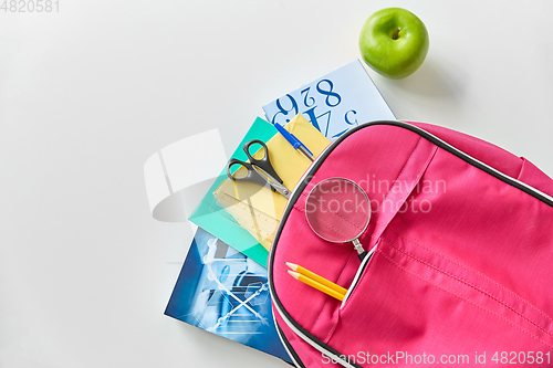 Image of backpack with books, school supplies and apple