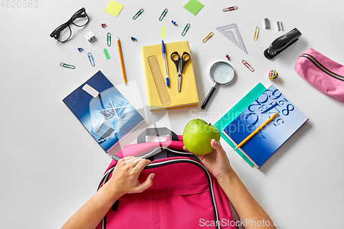 Image of hands with backpack, books and school supplies