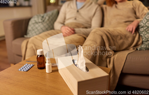 Image of box of tissues and drugs over sick couple at home