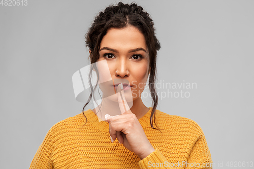 Image of young woman with pierced nose making hush gesture