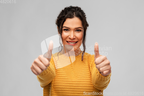 Image of happy smiling young woman showing thumbs up