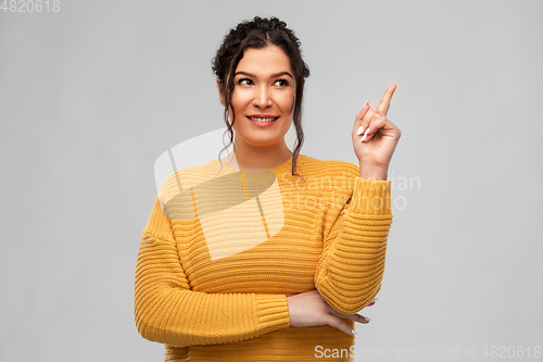 Image of happy smiling young woman pointing finger up