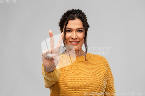 Image of happy smiling young woman showing peace sign