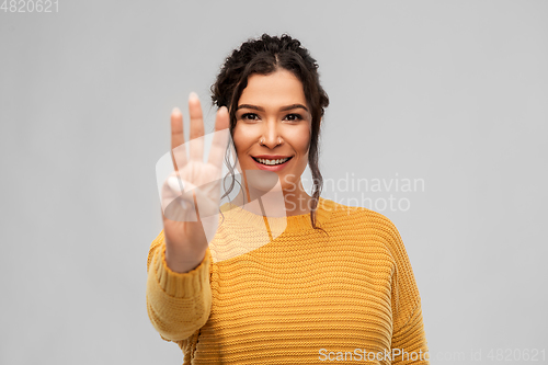 Image of happy woman in pullover showing three fingers