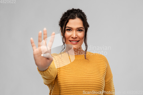 Image of happy woman in pullover showing four fingers