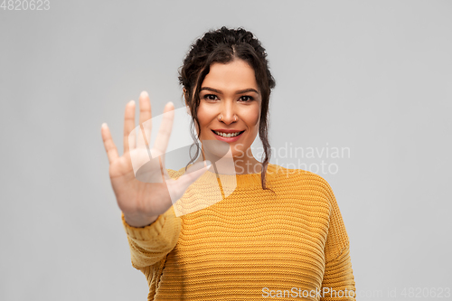 Image of happy woman in pullover showing five fingers
