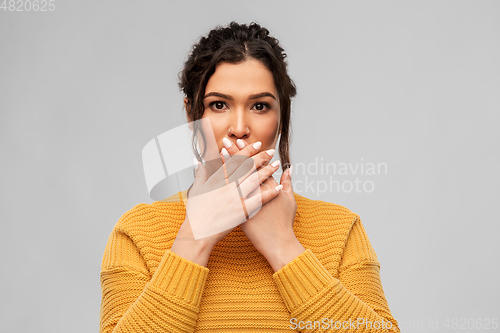 Image of scared woman clothing her mouth with hands