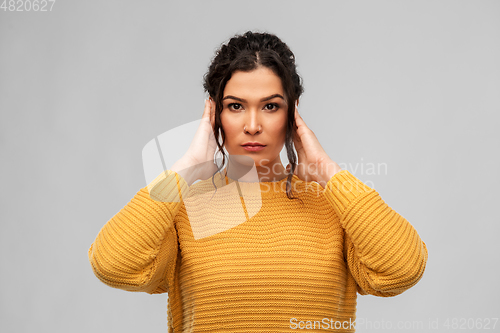 Image of serious woman closing ears with hands