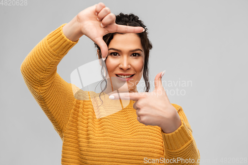 Image of happy young woman making frame with her fingers