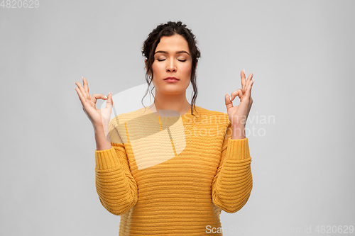 Image of young woman with pierced nose meditating