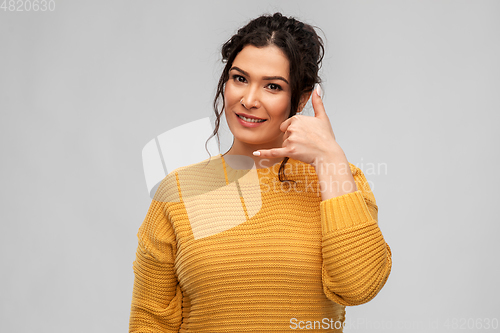 Image of young woman making phone call gesture