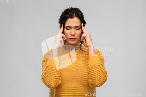 Image of stressed young woman holding to her head