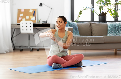 Image of woman with smart watch and exercise mat at home