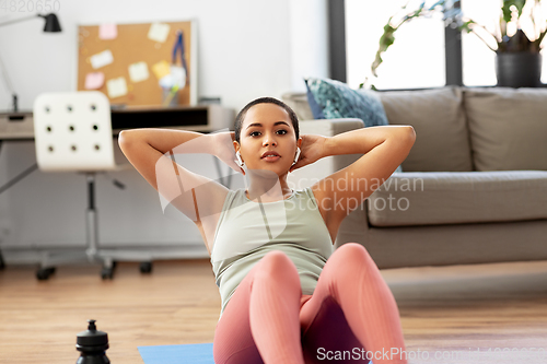 Image of african woman doing abdominal exercises at home