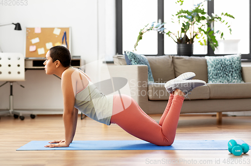 Image of african woman doing push-ups at home