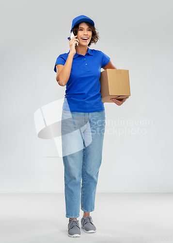 Image of delivery woman with parcel calling on smartphone