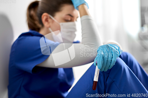 Image of sad doctor or nurse holding beaker with blood test