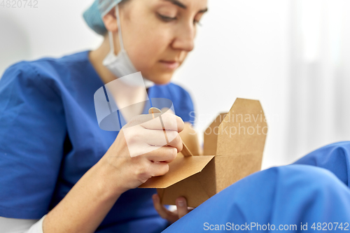 Image of sad doctor or nurse eating takeaway food from box