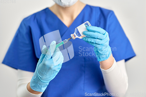 Image of doctor in face mask with syringe and medicine