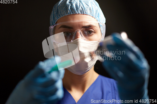 Image of doctor in face mask with syringe and medicine