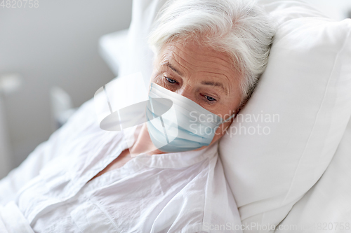 Image of old woman patient in mask lying in bed at hospital