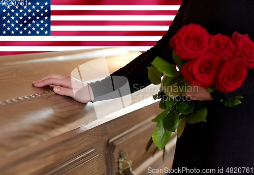 Image of woman with red roses and coffin over american flag