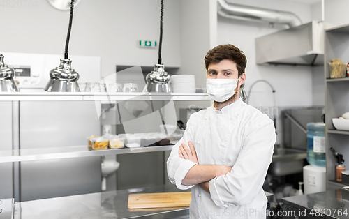 Image of male chef with in face mask at restaurant kitchen